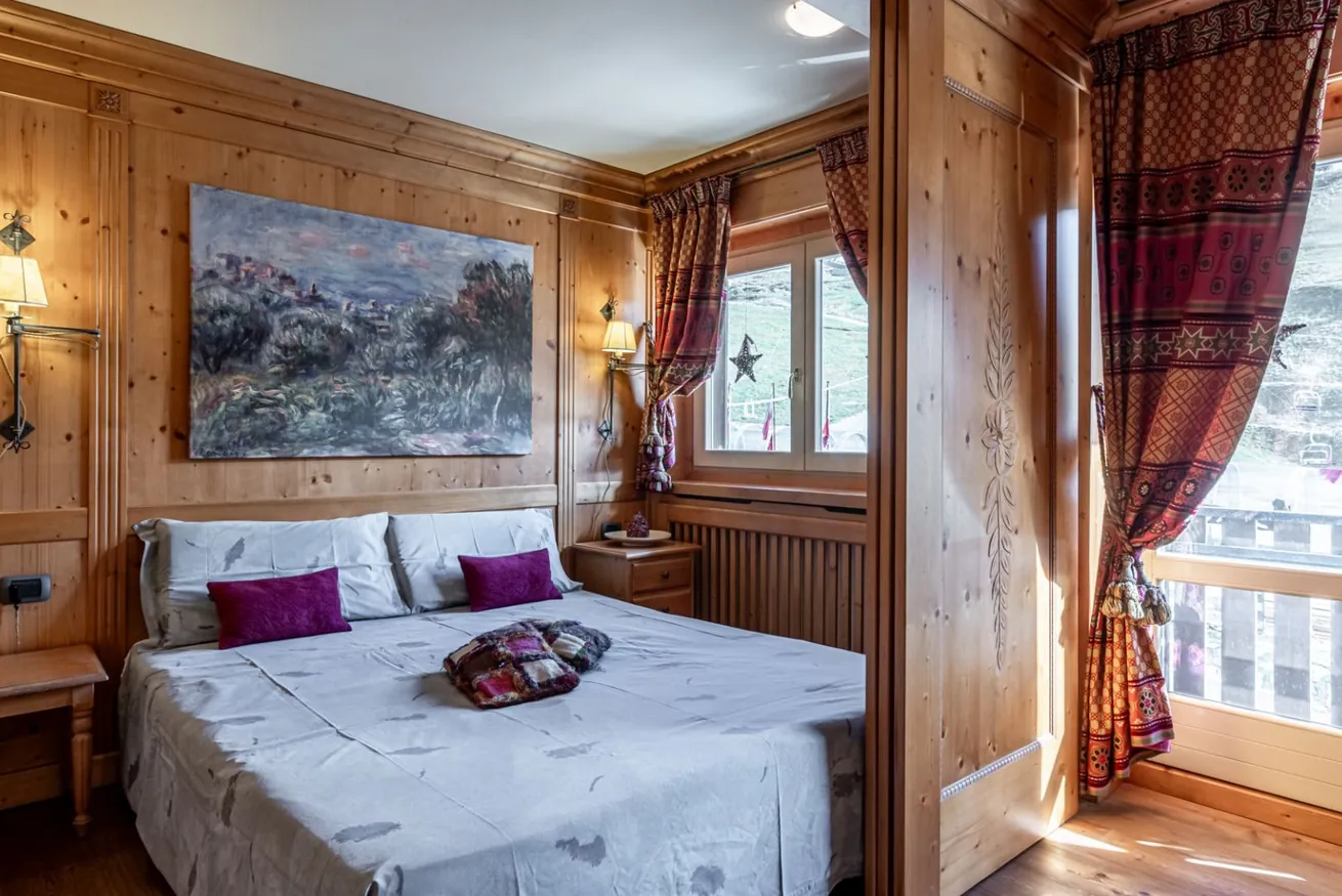 Camera matrimoniale con pareti in legno e tende rosse